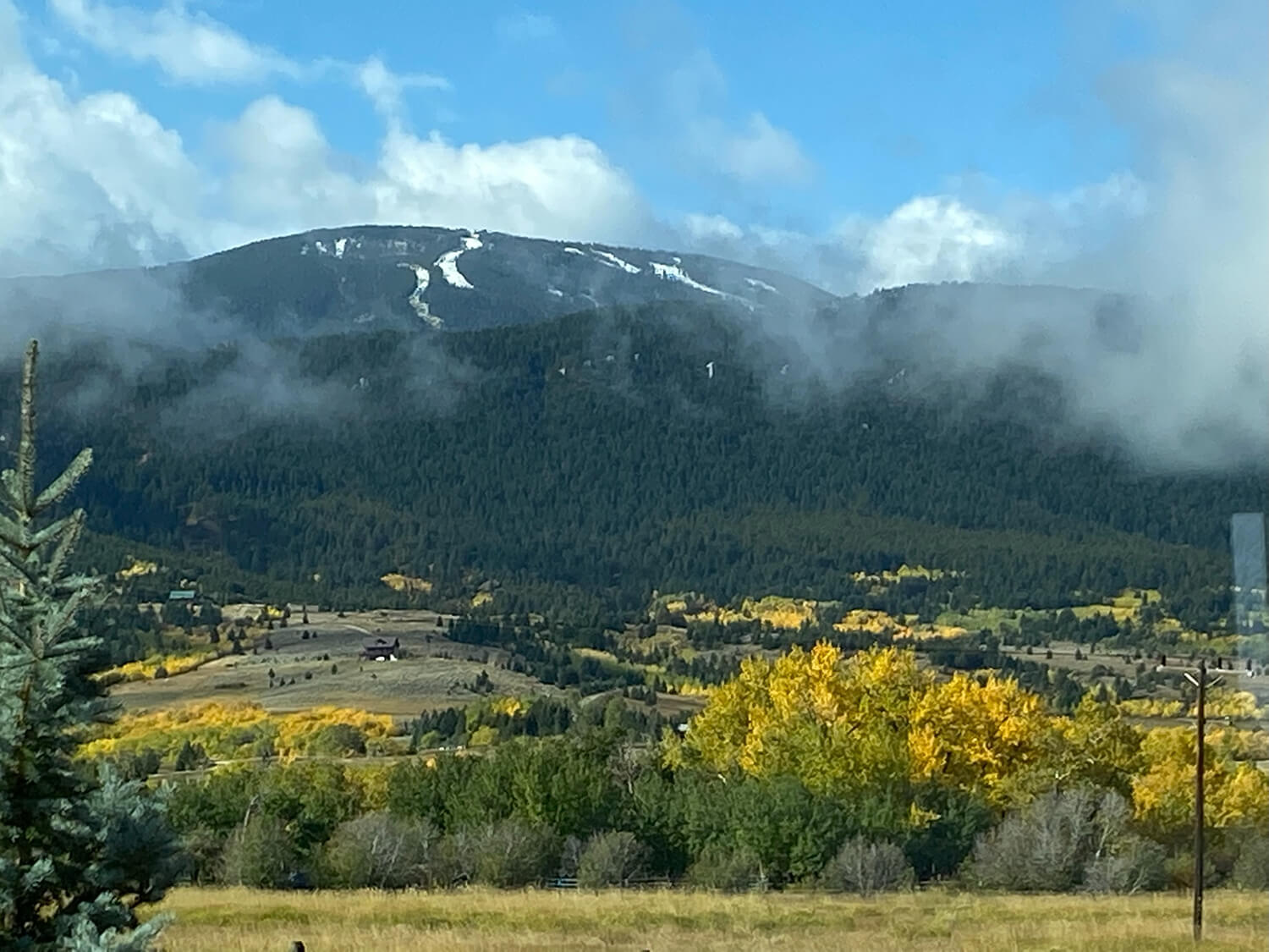 Mountain landscape with autumn trees and clouds.